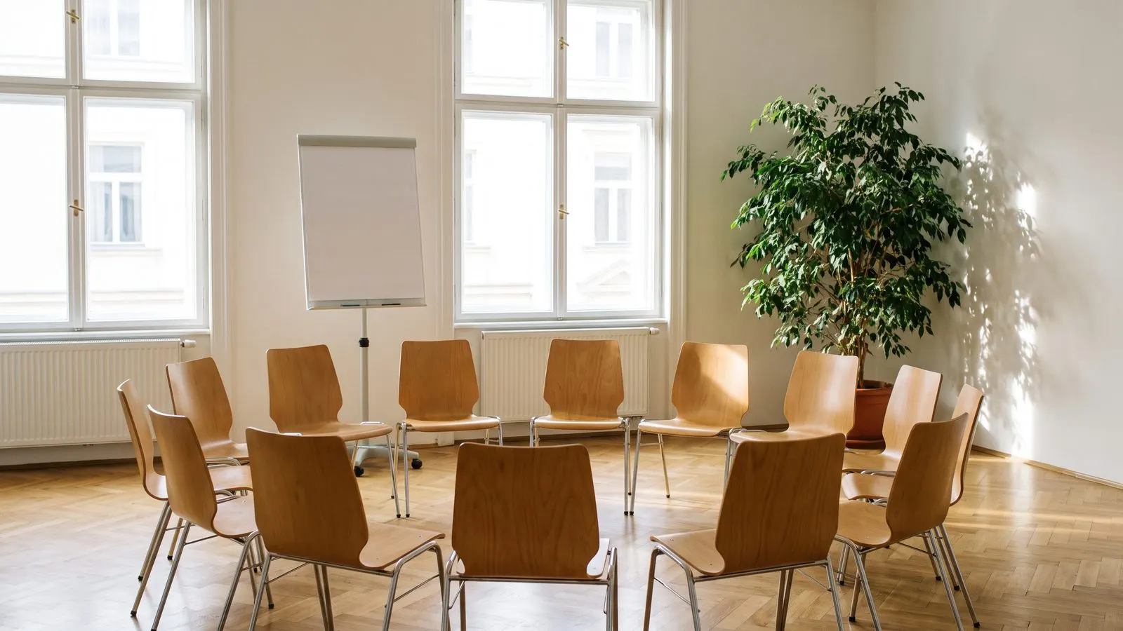 Heller Seminarraum mit Stuhlkreis und Flipchart ohne Beschriftung