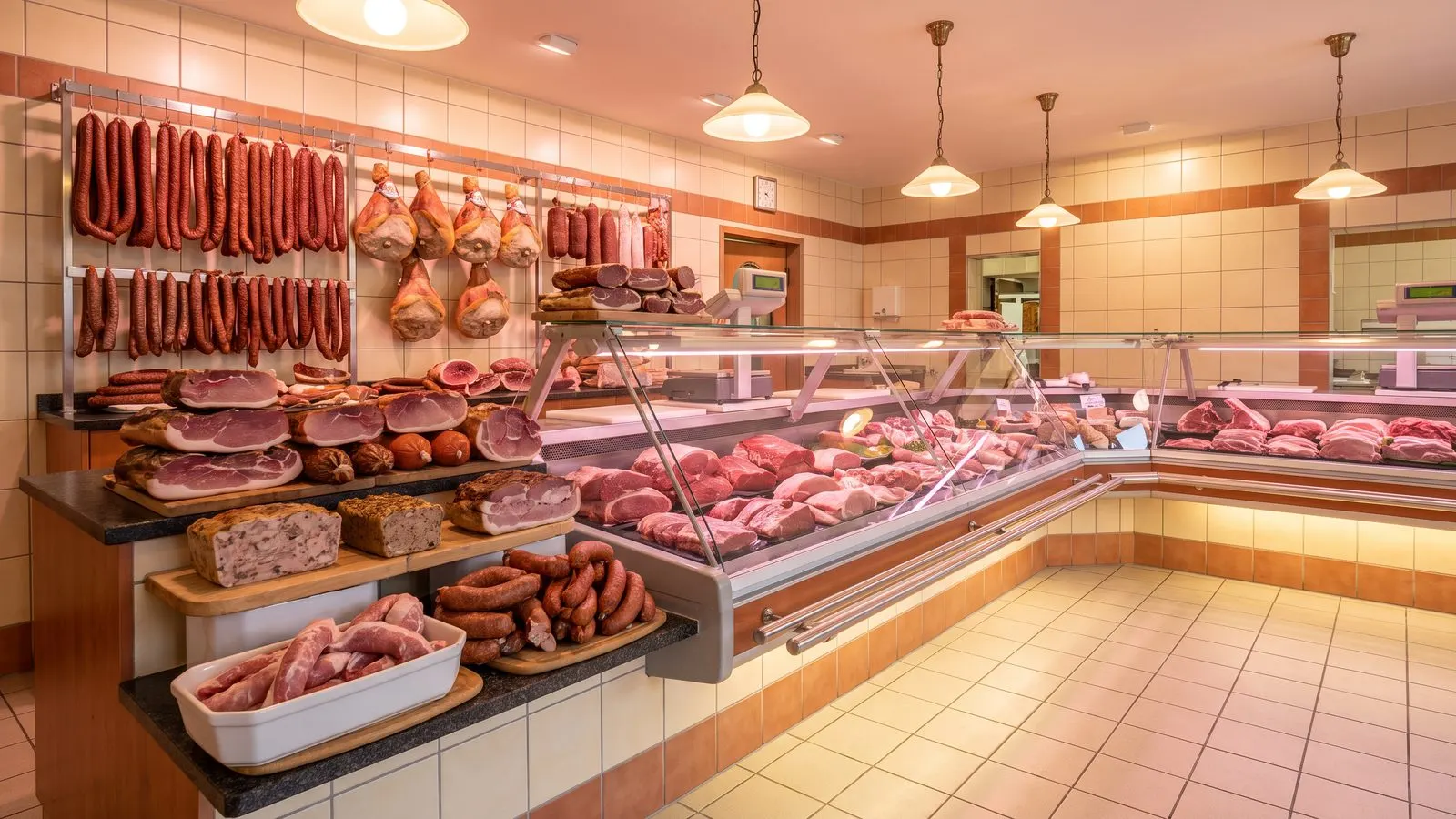 Metzgereitheke mit Wurstwaren und Fleischstuecken in sauberer Auslage
